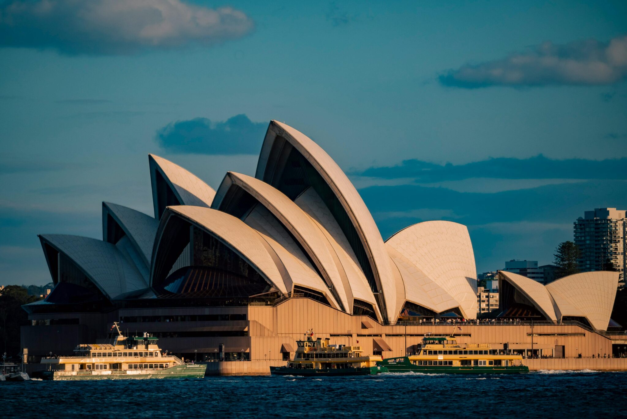 Iconic view of Sydney Opera House and ferries during sunset in Sydney, Australia.