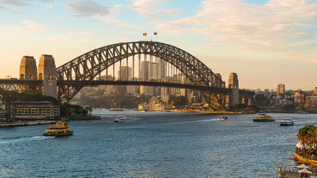 A stunning view of Sydney Harbour Bridge with ferries and cityscape during sunset, Sydney, Australia.