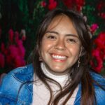 Portrait of a joyful woman smiling warmly with a vibrant floral backdrop.